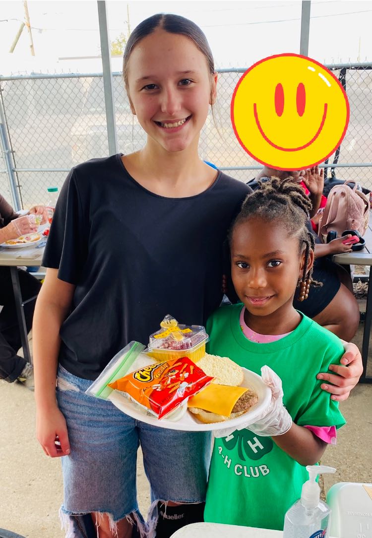 Two girls holding a plate of food.